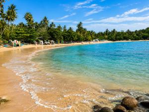 a beach with a bunch of people in the water at Solar House Hotel in Dickwella