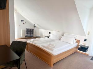 a bedroom with a large bed and a chair at Gästehaus Helbighof in Neustadt an der Weinstraße