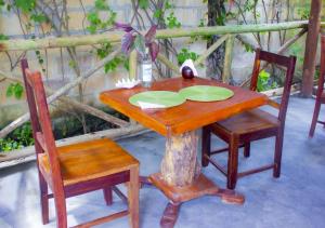 a wooden table with two chairs and a table with plates on it at Datch Hideaway in Kiwengwa