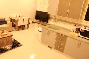 uma cozinha e sala de estar com um sofá e uma mesa em Aris Furnished Apartments em Buraydah