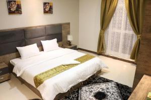 a bedroom with a large white bed and a window at Aris Furnished Apartments in Buraydah
