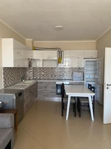 a kitchen with a white table and a table and chairs at ApartamentAbiBank in Elbasan