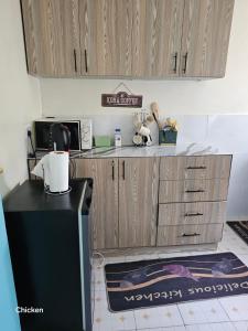 a kitchen with a black refrigerator and wooden cabinets at LaDee Homes Cozy 1 bedroom in Kakamega - Old National Housing Estate in Kakamega