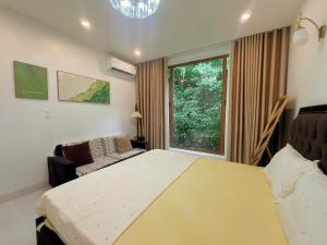a bedroom with a bed and a couch and a window at ROSE HOUSE Cat Ba island in Cat Ba