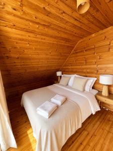 a bed in a wooden room with two towels on it at Chalet O Refúgio 2 in Penhas da Saúde
