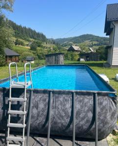a pool with a ladder and a chair next to it at pro100 house in Volosyanka