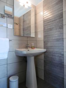 een badkamer met een witte wastafel en een spiegel bij Hôtel le Littoral in Lézardrieux