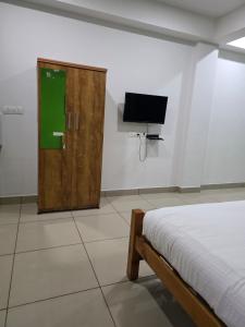 a bedroom with a bed and a tv on the wall at Barza Inn in Kakkanad