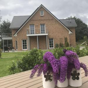 two white vases filled with purple flowers in front of a house at Noor-OG-mit-Studio-Nr-4 in Haby