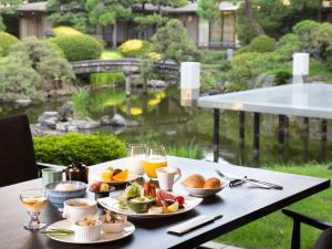 a table with plates of food and glasses of orange juice at Suisui Garden Ryokan (in the Art Hotel Kokura New Tagawa) in Kitakyushu