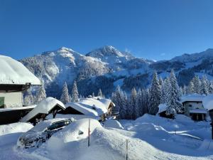 a house covered in snow with mountains in the background at Almhütten Sonnblick & Almfried in Sonnenalpe Nassfeld