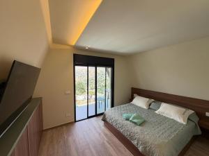 a bedroom with a bed and a sliding glass door at The Skyloft Tarchich - Panoramic Mountain Escapes in Aswāq aş Şafşāf +52 photos