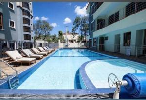 a large swimming pool with lounge chairs and a building at Lakeview 3BR Apartment Nakuru CBD in Nakuru
