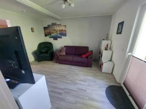 a living room with a purple couch and a refrigerator at Schöne Wohnung direkt am Bach in Neunkirchen am Sand