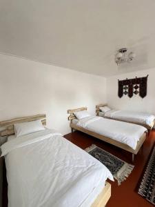 two beds in a room with white walls at Kairat guest house in Kashkaldak