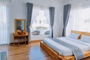 a bedroom with a bed and a desk and a window at villa Trung Nghĩa 5 in Da Lat