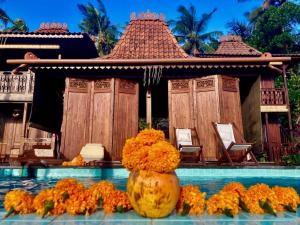 a vase filled with orange flowers in a swimming pool at Villa Hola Agung in Karangasem