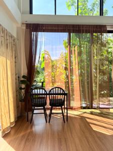 two chairs and a table in front of a large window at Alit House in Phra Nakhon Si Ayutthaya +4 photos