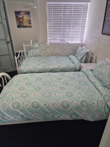 a bed with a comforter on top of it at Avocet Apartment in Perth