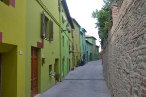 a narrow alley with green and yellow buildings at B&B da Baba in Ghizzano