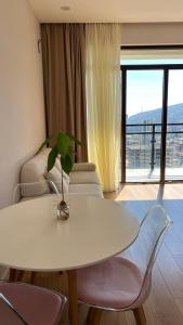 a white table and chairs in a living room with a window at 21 floor apartment in Tbilisi City