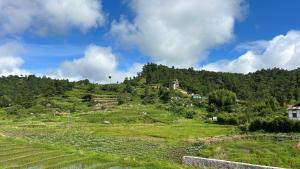 a grassy hill with a village on top of it at Serenity View Stay in Shillong