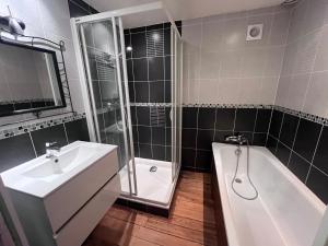 a bathroom with a sink and a tub and a shower at Maison 2 chambres 