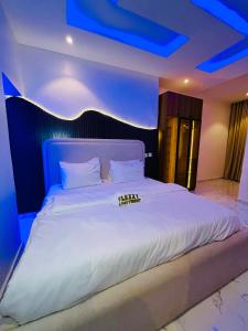 a bedroom with a large white bed with blue lights at Flexxy Apartment Hotel in Oshogbo