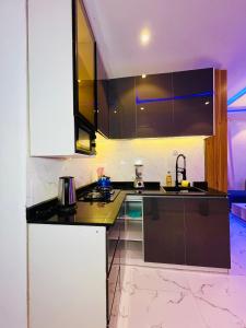 a kitchen with black and white cabinets and a sink at Flexxy Apartment Hotel in Oshogbo