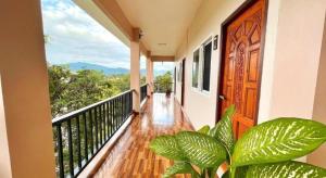 a balcony with a wooden door and green plants at janwareeresort in Sangkhla Buri