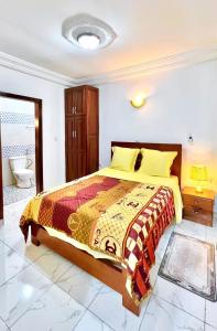 a bedroom with a large bed and a bathroom at Bj House in Douala