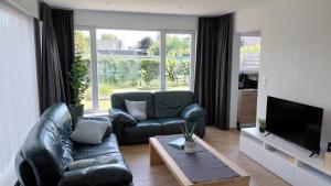 a living room with a leather couch and a television at B-SIDE Loppem in Zedelgem