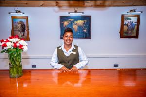 a woman sitting at a table in a room with flowers at Shose Farmhouse Chalets & Campsite in Moshi +90 photos