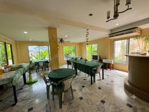 a restaurant with green tables and chairs and windows at Luxury Hotel ลักเซอรี่ โฮเทล in Ban Don Rak