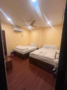 a room with two beds and a ceiling fan at Hotel Royal Palace in Kolkata