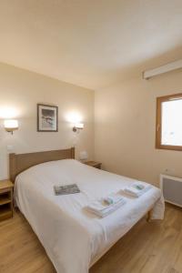 a bedroom with a white bed with two towels on it at Résidence Goélia Les Chalets Valoria in Valloire