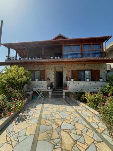 a large house with a stone patio in front of it at Sulejmanasi Rooms in Vlorë