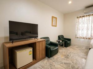a living room with a flat screen tv and two chairs at Luxury Hotel ลักเซอรี่ โฮเทล in Ban Don Rak +2 photos