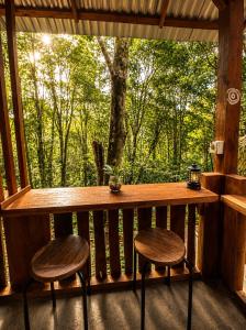 a porch with two stools and a table and a window at Tegal Luwih Cabin in Munduk