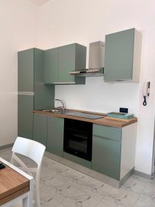 a kitchen with green cabinets and a white chair at SANTEA CASA vacanza in Grottaglie