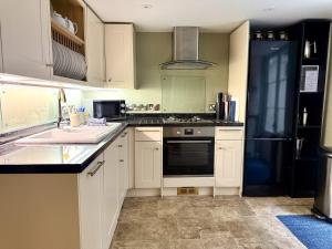 a kitchen with white cabinets and a black refrigerator at Abbey Mews in Bath