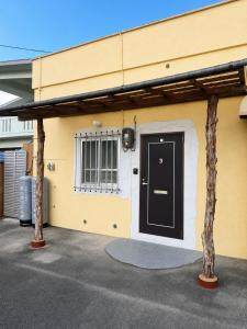 a yellow building with a black door and a window at Local LifeYOMITAN in Yomitan