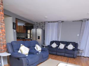 a living room with two blue couches with pillows at Eyesha Villa in Kampala