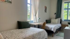 a bedroom with two beds and a desk and window at Hello Apartman in Budaörs