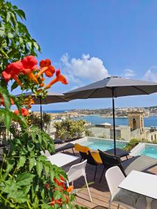 a patio with tables and umbrellas and a swimming pool at Ursulino Valletta in Valletta