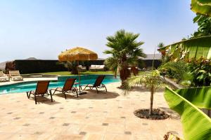 a patio with chairs and an umbrella and a pool at Exceptional Villa With Pool in Villaverde