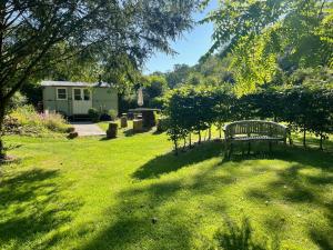 a park bench sitting in the grass in a yard at Dartmoor Shepherds Hut at The Shrubbery, River Walkham, Horrabridge, Yelverton in Tavistock