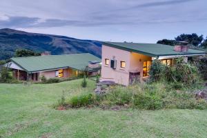 a house with a green roof on a field at Drakensberg Vultures View in Cathkin Park