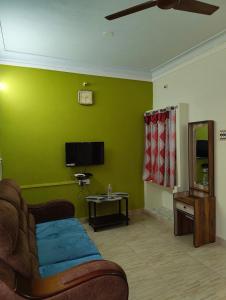 a living room with a couch and a green wall at RR Home Stay in Karaikal