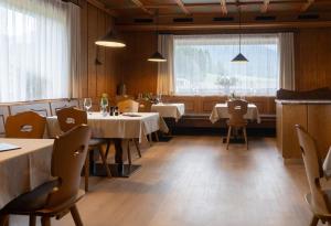 ein Restaurant mit Tischen und Stühlen und einem großen Fenster in der Unterkunft Hotel Scherer in Olang + 27 Fotos